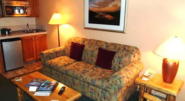 Photo of living area with couch, coffee table, side table, and partial view of the kitchenette